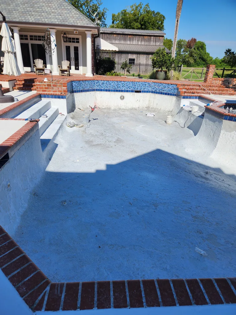 Drained pool with prepared interior, steps and blue tile during renovation in Bourg, Louisiana